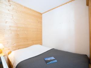 Un dormitorio con una cama con un libro. en Apartment Le Hameau du Borsat-1 by Interhome en Tignes