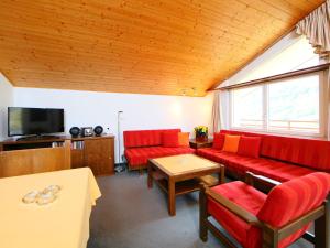 uma sala de estar com sofás vermelhos e uma televisão em Apartment Ringstrasse - Utoring-31 by Interhome em Leukerbad