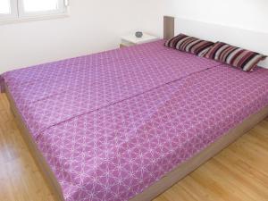 a bed with a purple comforter on top of it at Apartment Andjelka-1 by Interhome in Trogir