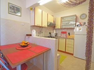eine kleine Küche mit einem Tisch und einem weißen Kühlschrank in der Unterkunft Apartment Matal by Interhome in Podorjak
