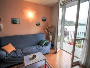 sala de estar con sofá azul y balcón en Apartment Franco by Interhome, en Porto Ceresio