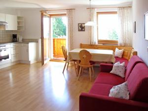 a living room with a red couch and a table at Apartment Obermüllerhof-2 by Interhome in Maranza