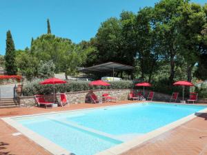 una piscina con sombrillas y sillas rojas en Apartment Tortora by Interhome, en Santa Luce