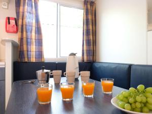 una mesa con cuatro vasos de zumo de naranja y un tazón de uvas en Holiday Home Rosapineta Camping Village-2 by Interhome en Rosapineta