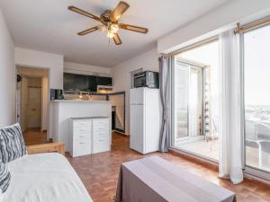 a living room with a ceiling fan and a kitchen at Apartment Le Capri-1 by Interhome in Cap d'Agde