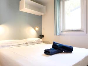 białe łóżko z niebieską torbą. w obiekcie Holiday Home Camping Butterfly-2 by Interhome w mieście Peschiera del Garda +22 zdjęcia