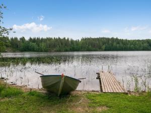 un bateau sur la rive d'un lac avec un quai dans l'établissement Holiday Home Ahvenranta by Interhome, à Kosula
