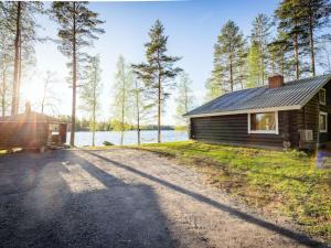 a cabin with a road next to a body of water at Holiday Home Tatunmökki by Interhome in Huuhanaho
