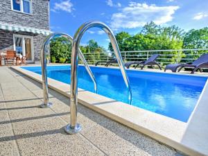 a swimming pool with two metal hand rails next to a swimming pool at Holiday Home Dante by Interhome in Marčelji +21 photos
