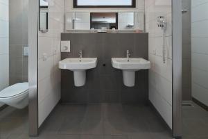 ein Badezimmer mit zwei Waschbecken und einem WC in der Unterkunft Hotel Babylon Heerhugowaard - Alkmaar in Heerhugowaard