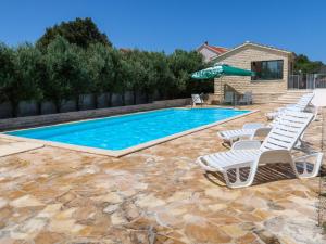 a swimming pool with lounge chairs and an umbrella at Holiday Home Camp Marko - ROZ335 by Interhome in Zečevo