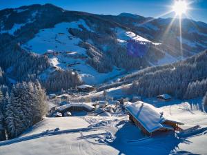 a snow covered mountain with a village with the sun in the sky at Apartment Chalet Edelweiß by Interhome in Auffach