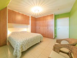 a bedroom with a bed and a chair in it at Apartment Goldsands II 402 Top floor with parking by Interhome in De Haan