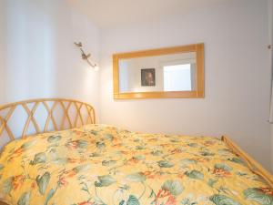 a bed with a floral bedspread and a mirror at Apartment Le Sunset-Cap Sud-20 by Interhome in Cap d'Agde