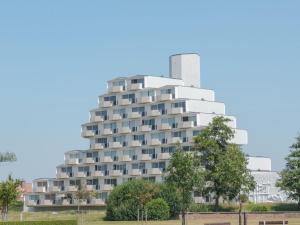 a tall white building with trees in front of it at Studio High in the sky with amazing views by Interhome in De Haan
