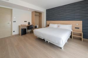 a bedroom with a large white bed and a desk at Hotel Spa Meiga do Mar in Caldebarcos