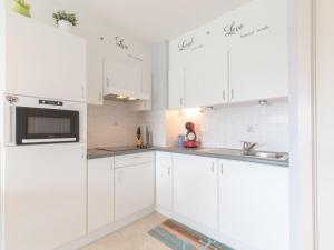 a white kitchen with white cabinets and a sink at Studio Bowie with shared pool by Interhome in De Haan +11 photos