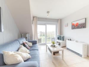 a living room with a blue couch and a tv at Studio Bowie with shared pool by Interhome in De Haan +9 photos