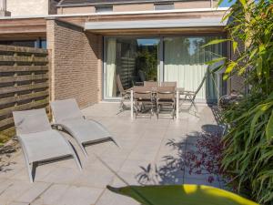 a patio with a table and chairs on it at Holiday Home Stella Maris with garage and garden by Interhome in De Haan