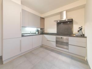 a white kitchen with white cabinets and a sink at Holiday Home Stella Maris with garage and garden by Interhome in De Haan