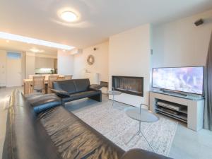 a living room with a couch and a flat screen tv at Holiday Home Stella Maris with garage and garden by Interhome in De Haan