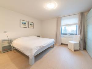 a bedroom with a bed and a window and a chair at Holiday Home Stella Maris with garage and garden by Interhome in De Haan