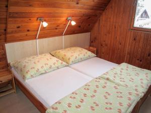 a bed in a wooden room with two lights at Chalet Dehtáře by Interhome in Hluboká nad Vltavou