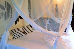 a bed with white curtains and pillows on it at Pousada Jacarandá by Rivaj in Trancoso