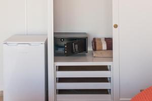 a small kitchen with a microwave and a refrigerator at Hostal Los Pinos in Es Cana