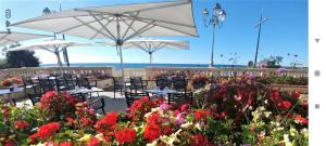 a patio with tables and chairs with flowers and umbrellas at Ancienne sous-prefecture in Les Sables-dʼOlonne
