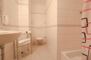 Baño blanco con lavabo y aseo en Petul Apart Hotel Ernestine, en Essen