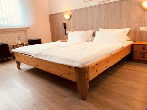 ein großes Bett in einem Schlafzimmer mit einem Kopfteil aus Holz in der Unterkunft Hotel Orthwein -kostenfreie Parkplätze- in Cölbe