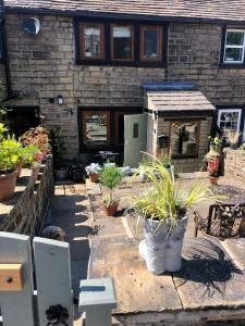 a garden with potted plants in front of a building at Wuthering Cottage - Central, Stylish, Cosy, Comfy in Haworth