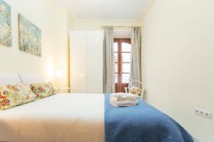 um quarto com uma cama branca e um cobertor azul em AlohaMundi Zaragoza IV em Sevilha