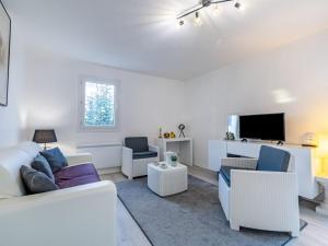 ein Wohnzimmer mit einem Sofa, Stühlen und einem TV in der Unterkunft Apartment Le Vert Coteau-3 by Interhome in Touques