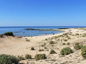 a sandy beach with people swimming in the ocean at Holiday Home Happy Premium by Interhome in Torre Lapillo
