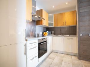 uma cozinha branca com armários e electrodomésticos em madeira em Apartment Rond Point des Pistes - Val Claret-17 by Interhome em Tignes