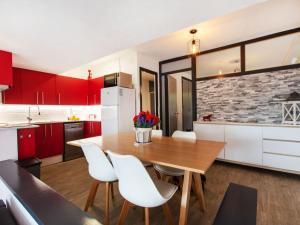 een keuken met rode kasten en een houten tafel en witte stoelen bij Apartment Rojo by Interhome in Tossa de Mar