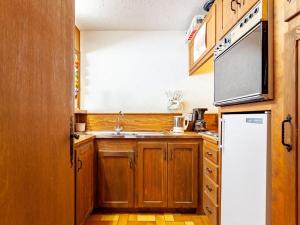 cocina con armarios de madera y nevera blanca en Apartment La Christaz-6 by Interhome, en Saint-Gervais-les-Bains