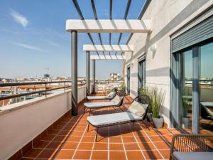 a balcony with chairs and tables on a building at Limehome Madrid Calle de Don Ramón de la Cruz in Madrid