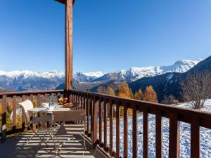 einen Tisch und Stühle auf einem Balkon mit schneebedeckten Bergen in der Unterkunft Apartment Les Alpages du Corbier-10 by Interhome in Le Corbier
