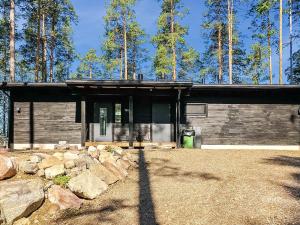 a small house with a stone wall and trees at Holiday Home Villa saimaan joutsenlahti by Interhome in Äitsaari