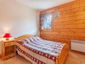 ein Schlafzimmer mit einem Bett und einer Holzwand in der Unterkunft Apartment Marmottes A6 by Interhome in Les Menuires
