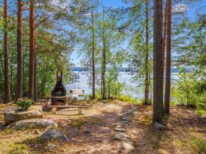 eine Feuerstelle im Wald neben einem See in der Unterkunft Holiday Home Honkaniemi by Interhome in Hiukkajoki