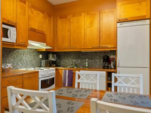 a kitchen with wooden cabinets and a white refrigerator at Holiday Home Puolikuu a7 by Interhome in Sirkka