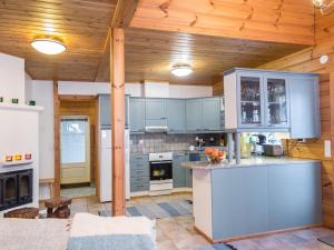 Elle comprend une grande cuisine avec des placards bleus et un plafond en bois. dans l'établissement Holiday Home Tahkontupa by Interhome, à Tahkovuori