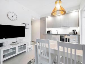 a white kitchen with a dining table and a clock at Holiday Home Tunturinlaita c6 by Interhome in Sirkka