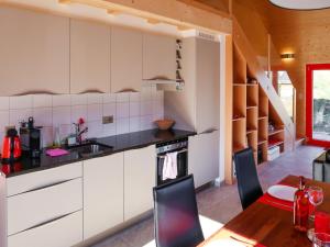 cocina con armarios blancos, mesa y sillas en Chalet Les Silènes by Interhome, en Saclentse