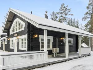 a log cabin with a porch in the snow at Holiday Home Rapsakka a by Interhome in Sirkka