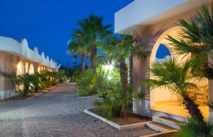 a walkway in front of a building with palm trees at Garden Hotel Ripa in Vieste